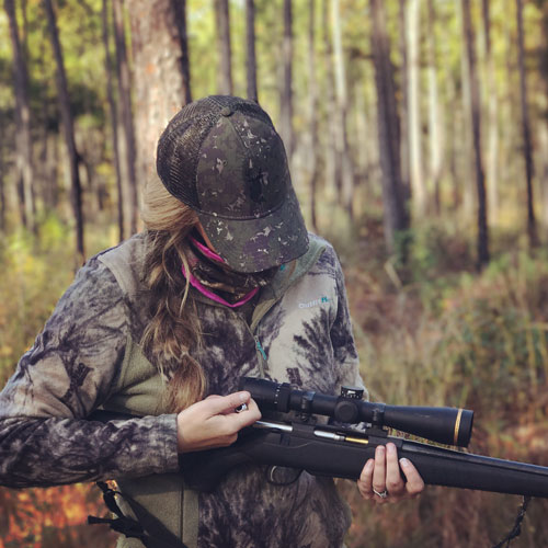 Female hunter loading rifle