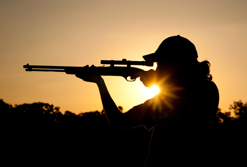 Silhouette of a young man shooting long rifle