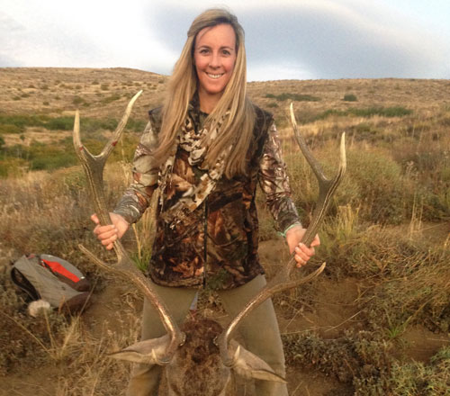 Female hunter holding up Red Stag antlers after hunt