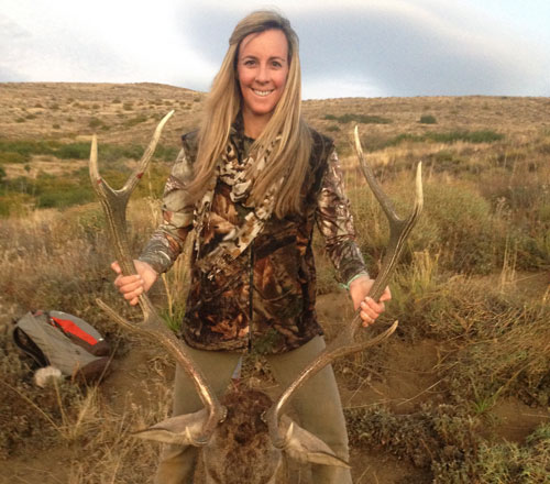 Female hunter holding up Red Stag antlers after hunt