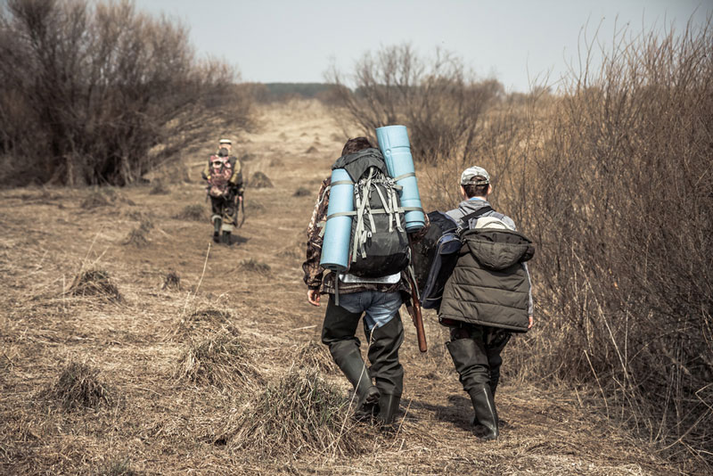 Three hunters with big packs walking through wilderness