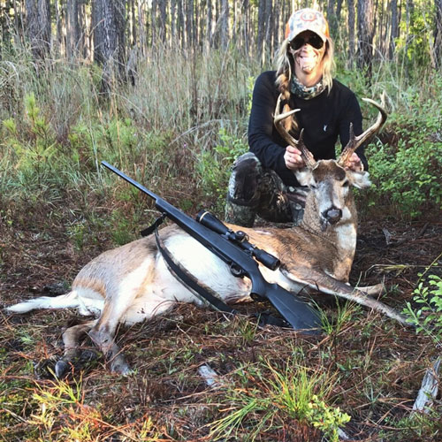 Female hunter posing near downed deer