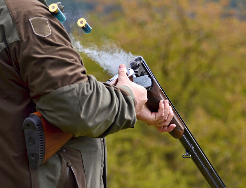 Man discharging shotgun shells from firearm after shots