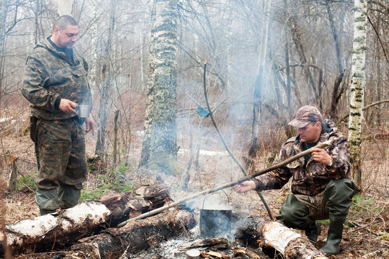 Two hunters cooking dinner over a campfire