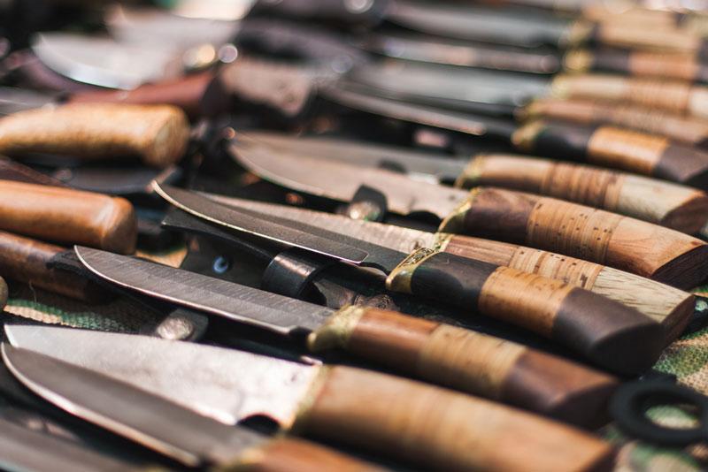 Assortment of wood handle hunting knives laying on table