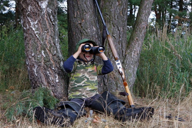 Boy hunting with binoculars